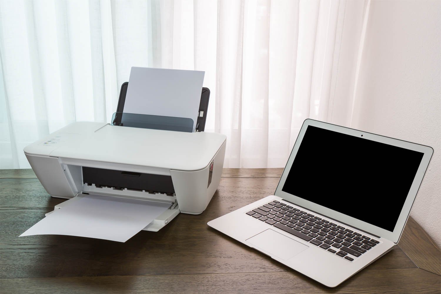 impressora multifuncional HP ao lado de notebook em cima de uma mesa