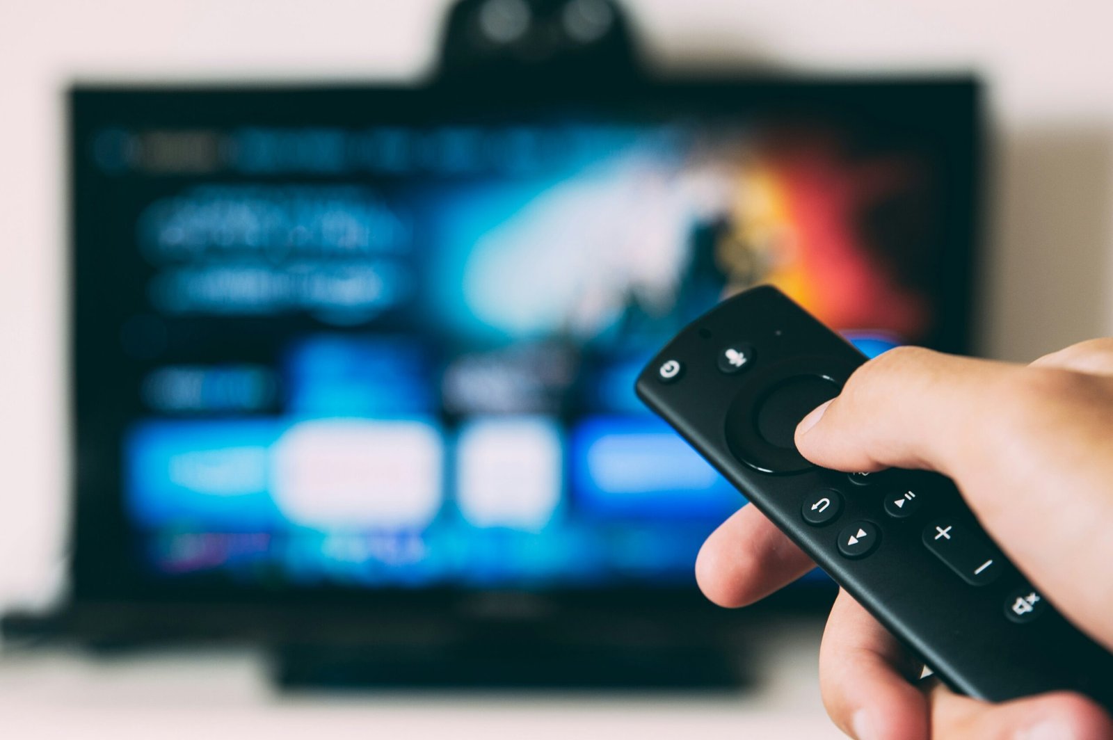 pessoa com controle remoto na mao mudando o canal de smart tv