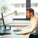 homem sentado em mesa em escritório usando acessórios para computador