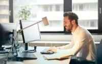 homem sentado em mesa em escritório usando acessórios para computador