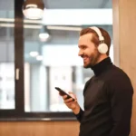 Homem com celular na mão usando fones de ouvido Bluetooth da Philips
