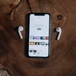 Um par de fones de ouvido sem fio da Lenovo ao lado de um celular em cima de uma mesa