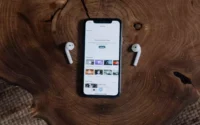 Um par de fones de ouvido sem fio da Lenovo ao lado de um celular em cima de uma mesa