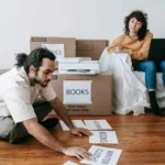 Moça sentada no sofá com notebook e moço sentado no chão usando uma impressora Epson
