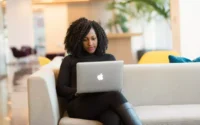 Moça usando um dos notebooks Apple sentada em sofá