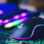 Mouse gamer ao lado de teclado sobre mousepad em cima de uma mesa