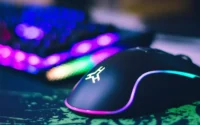 Mouse gamer ao lado de teclado sobre mousepad em cima de uma mesa