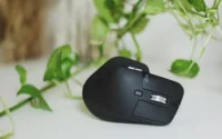 Um dos mouses Logitech em cima de uma mesa perto de vaso de plantas