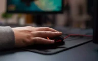 pessoa usando um mouse sobre um mousepad em cima de uma mesa de computador