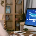 Moço olhando para tela de computador onde está aberta uma página de hospedagem de site para escolher