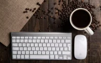 Teclado para PC com bom custo-benefício ao lado de mouse da Apple e xícara de café sobre uma mesa