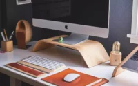 Teclado de computador da Apple sobre escrivaninha ao lado de mouse da Apple e computador de mesa da Apple