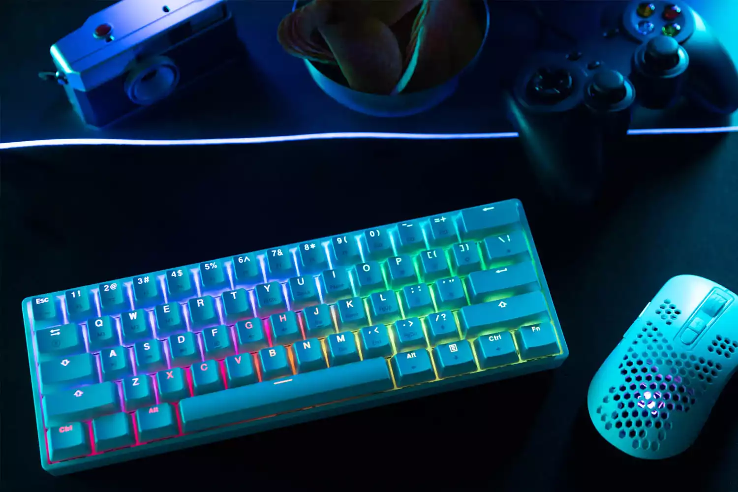 Teclado iluminado para PC ao lado de mouse em cima de uma escrivaninha