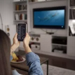 moça apontando celular para smart tv de 40 polegadas