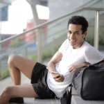 moço sentado na escada com roupas esportivas usando um fone de ouvido esportivo