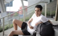 moço sentado na escada com roupas esportivas usando um fone de ouvido esportivo