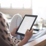 moça sentada olhando tablet barato