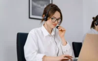 moça usando fone de ouvido com microfone sentada em frente a um computador