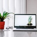 notebook sobre uma mesa em escritório home office ao lado da janela
