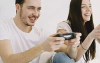 casal segurando controles e jogando em um dos consoles de videogame baratos