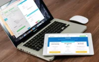 notebook aberto com tablet em cima com a tela mostrando plano de hospedagem de loja virtual