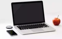 computador portatil em cima de uma mesa ao lado de maçã e celular