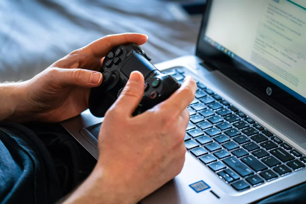 notebook-gamer-capa Mãos de jovem segurando controle joystick jogando em notebook gamer