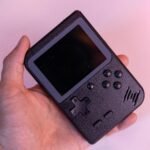 mão de homem segurando um videogame portátil barato