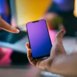 mão de mulher segurando smartphone e outra mão feminina apontando para ele ilustrando vantagens do celular multilaser