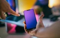mão de mulher segurando smartphone e outra mão feminina apontando para ele ilustrando vantagens do celular multilaser