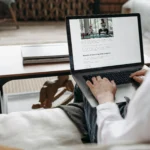 mulher sentada no sofá usando notebook ilustrando hospedagem de site anual