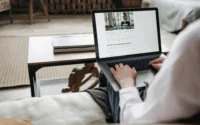 mulher sentada no sofá usando notebook ilustrando hospedagem de site anual