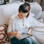 moça sentada no sofá usando um tablet da xiaomi com uma caneta digital