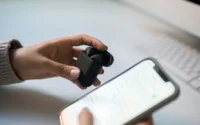 mulher segurando fone de ouvido bluetooth em uma mão e na outra um celular ilustrando fone de ouvido xiaomi