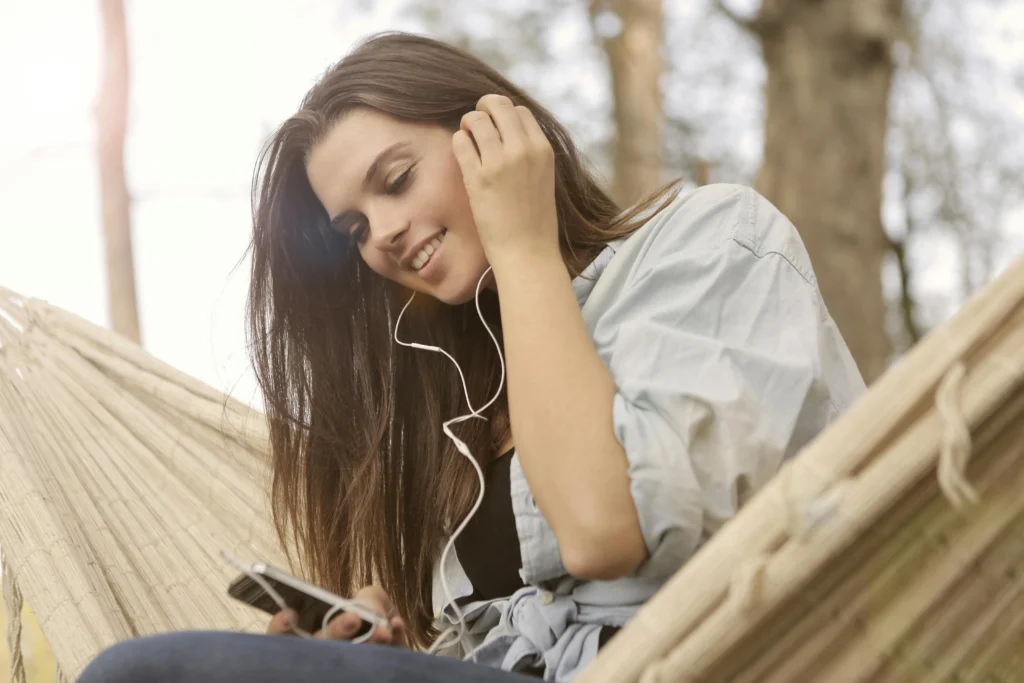 moça com fone de ouvido na orelha segurando celular ilustrando fones de ouvido da Samsung