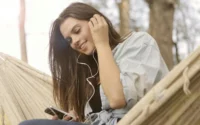 moça com fone de ouvido na orelha segurando celular ilustrando fones de ouvido da Samsung