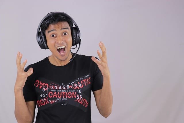 moço com cara engraçada utilizando um fone de ouvido tipo concha ilustrando o assunto dos tipos de fone de ouvido que existem